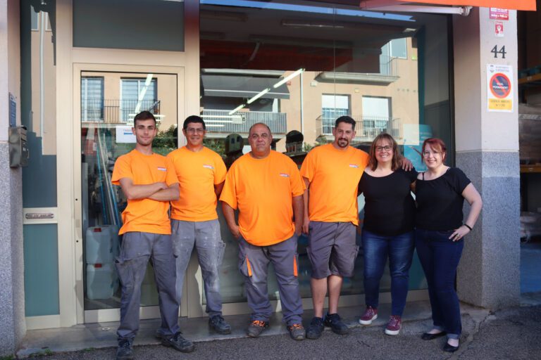 Exterior de un local de mantenimiento de piscinas junto con 6 empleados con uniformes de color naranja y negro